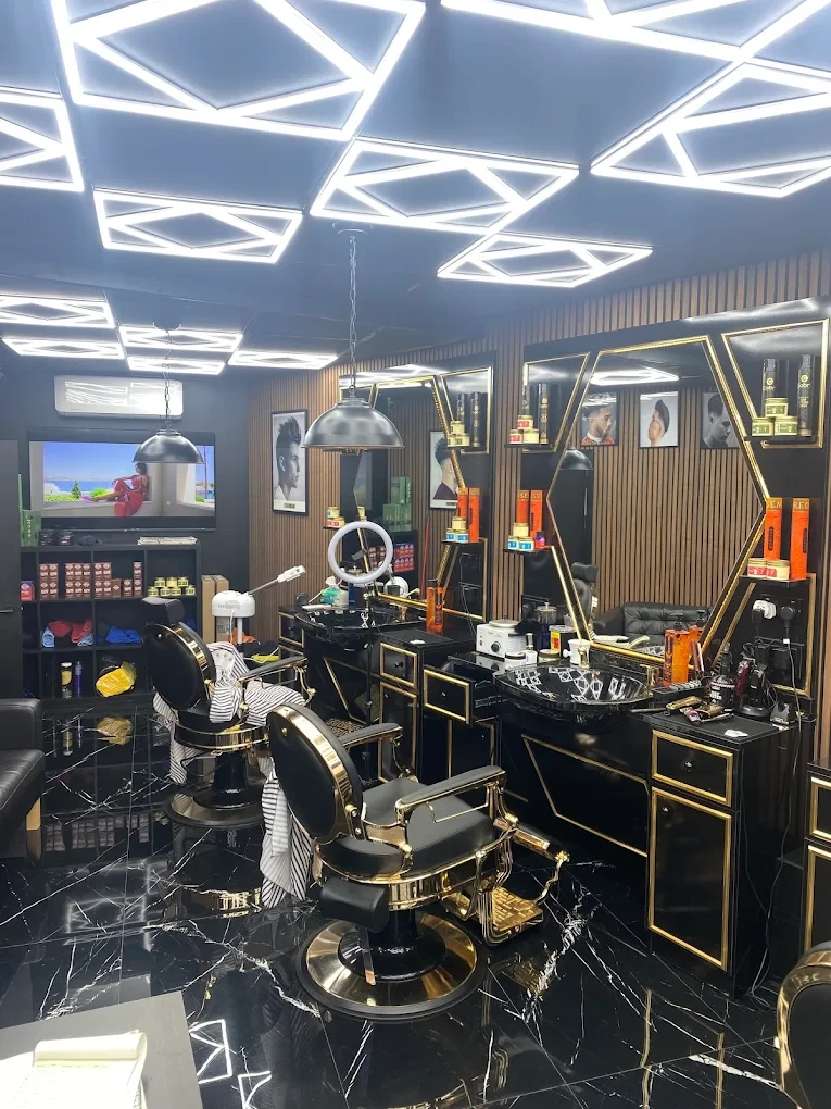 Black and gold barber chairs in front of hexagon mirrors under geometric LED ceiling lights