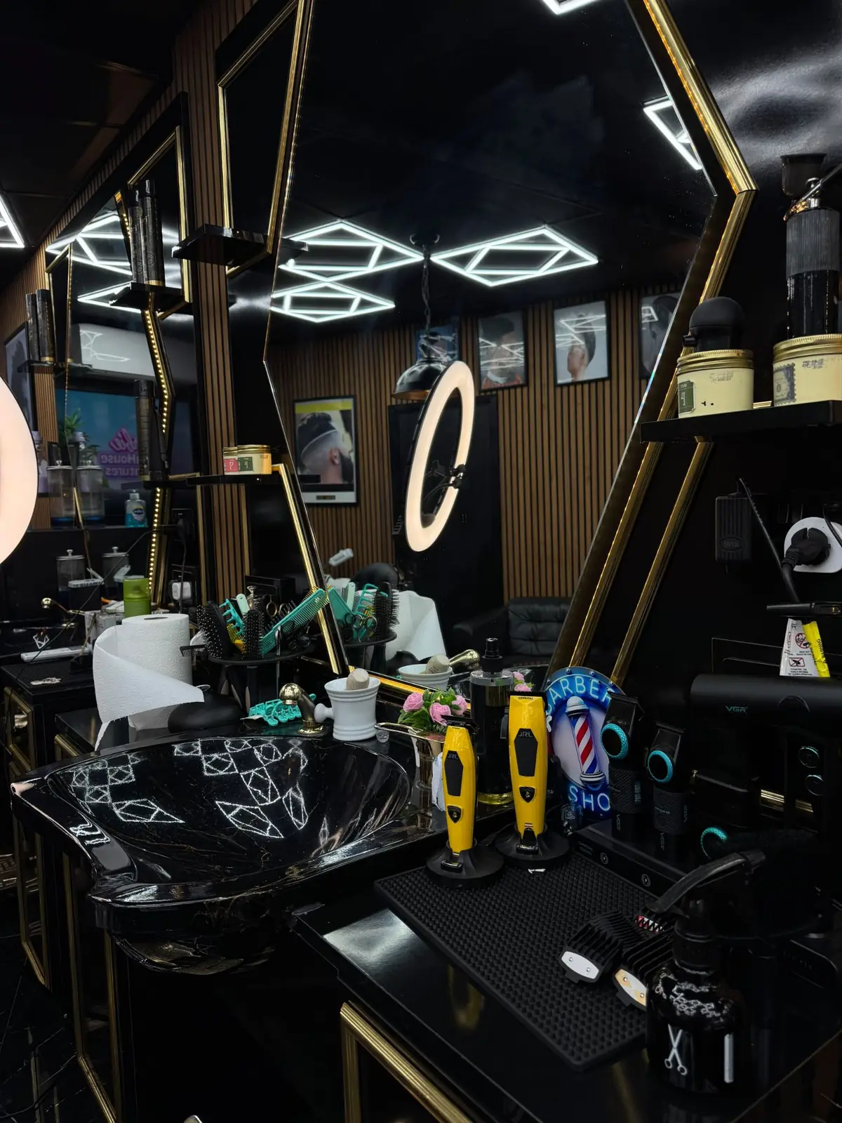 A station with a black marble basin, clippers and a gold hexagon mirror